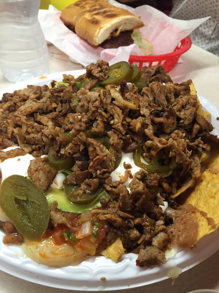Loaded super nachos with grilled meat, jalapeños, sour cream, and avocado