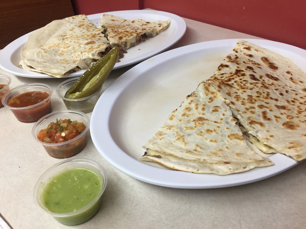 Two large quesadillas suizas with sides of salsa verde, roja, pico de gallo, and jalapeño